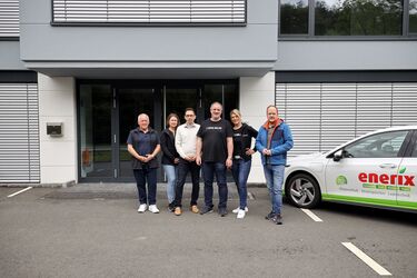 Repräsentanten der Stadt Kirchen (Riccarda Vitt, Tim Kraft und Andreas Hundhausen) mit Ulrich Haas (Ortsvorsteher Wehbach) sowie Alan und Nicole Hughes von Enerix Westerwald vor einem Gebäude in Wehbach